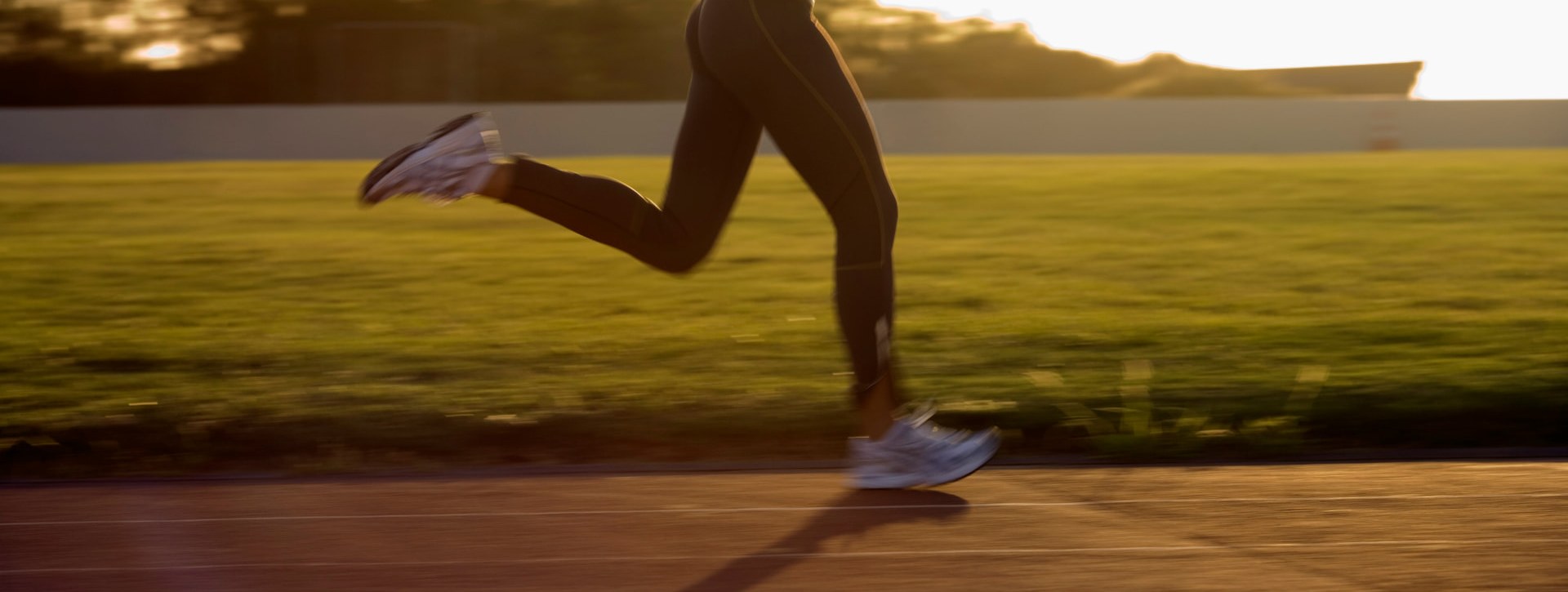 Runner's legs and feet on a track at sunrise